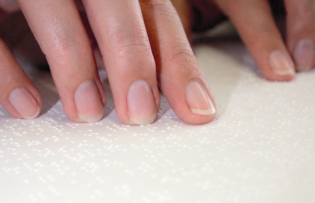 Finger gleiten über eine Text in Braillschrift