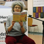 Thomas Zwerinas Frau liest sitzend aus seinem Buch "Eine Fingerkuppe Freiheit"