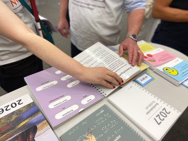 Standbesucher lesen mit den Händen in einem Buch.